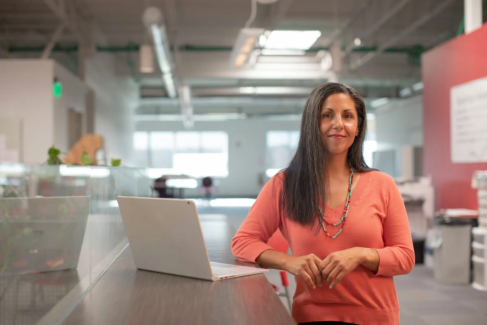 A friendly customer-success professional standing at a laptop, ready to help