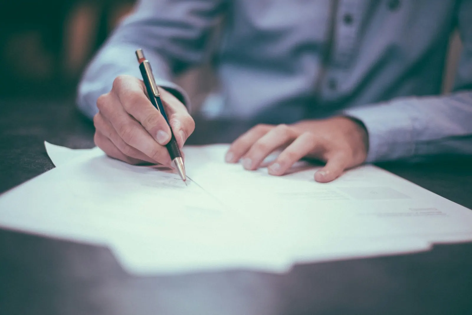 A finance professional signing a document at a desk
