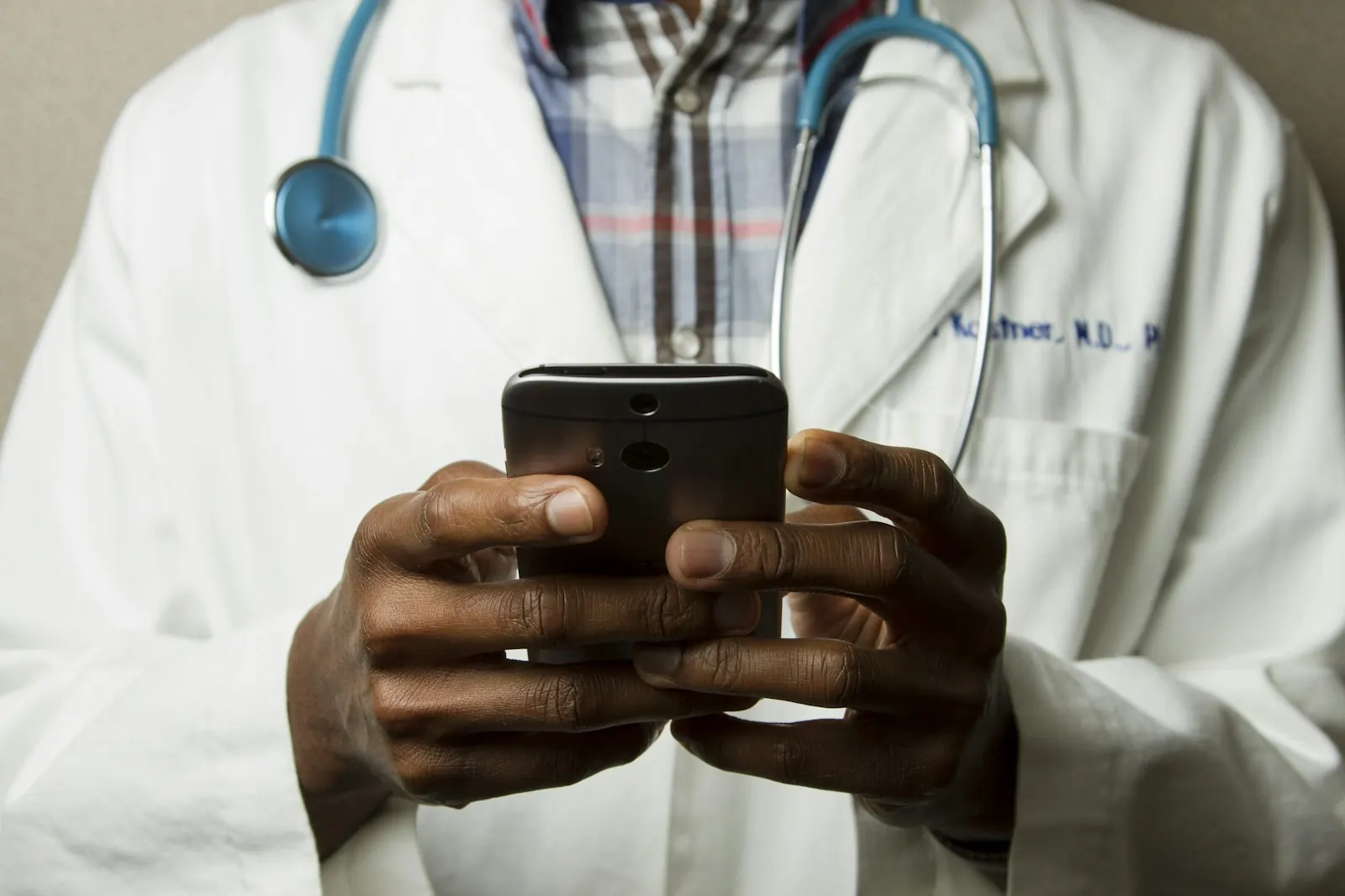 A doctor in a white coat checking a message on a smartphone