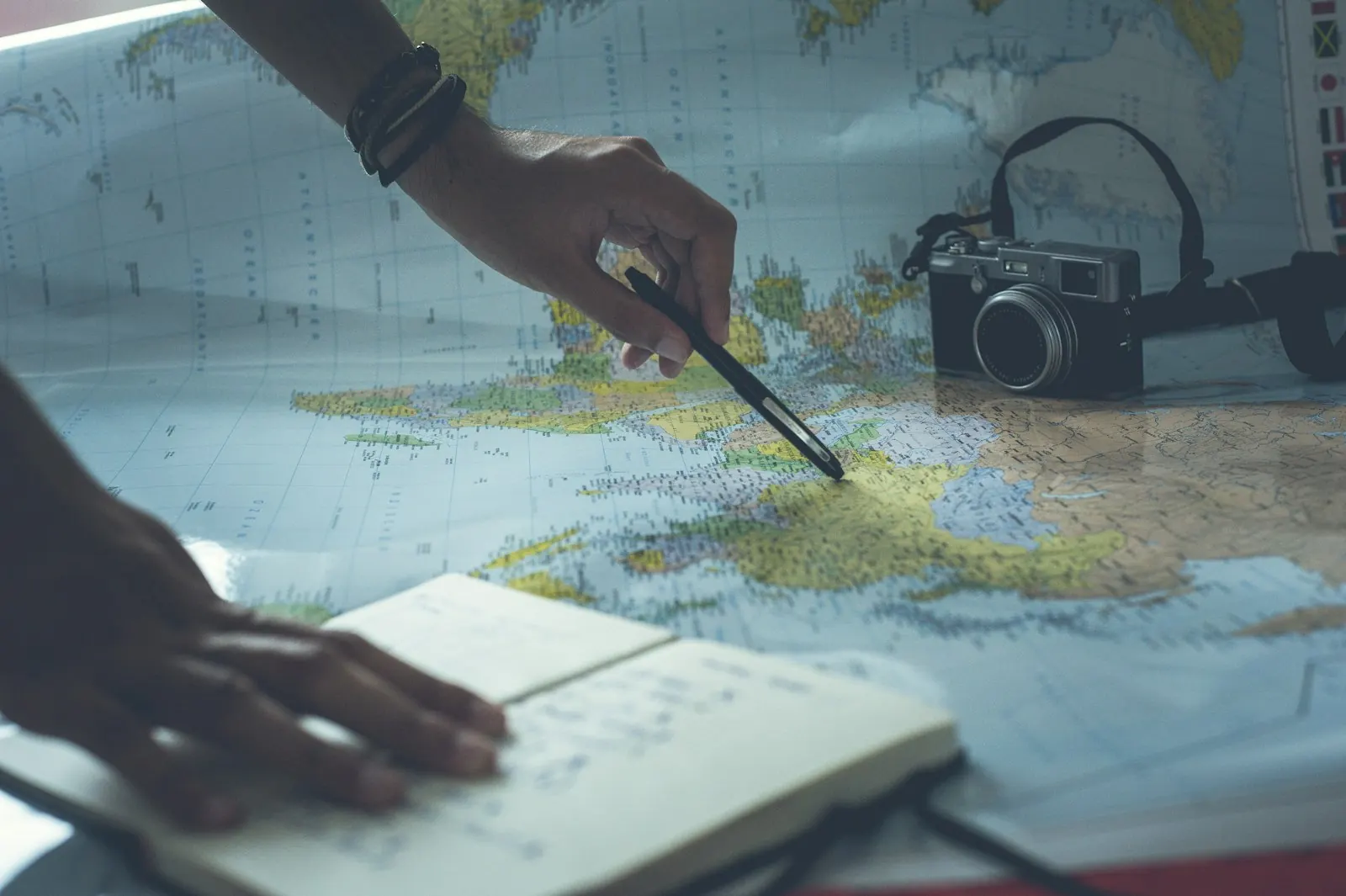 A traveller planning a route on a map with a camera and notebook