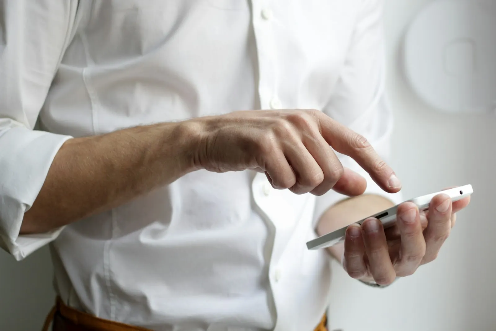 A professional in a white shirt reading a text message on a smartphone