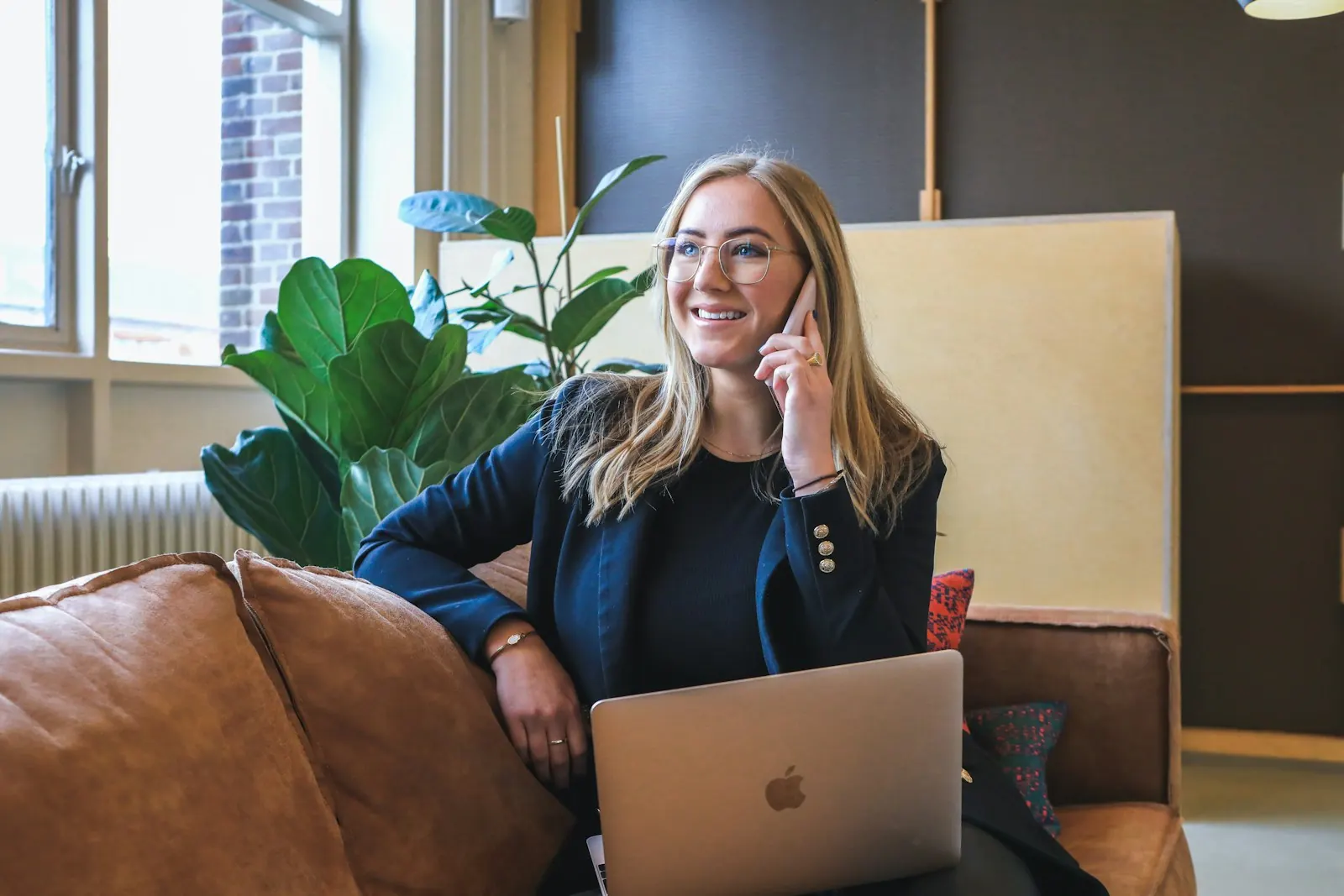 A businesswoman taking a phone call at her desk with a laptop