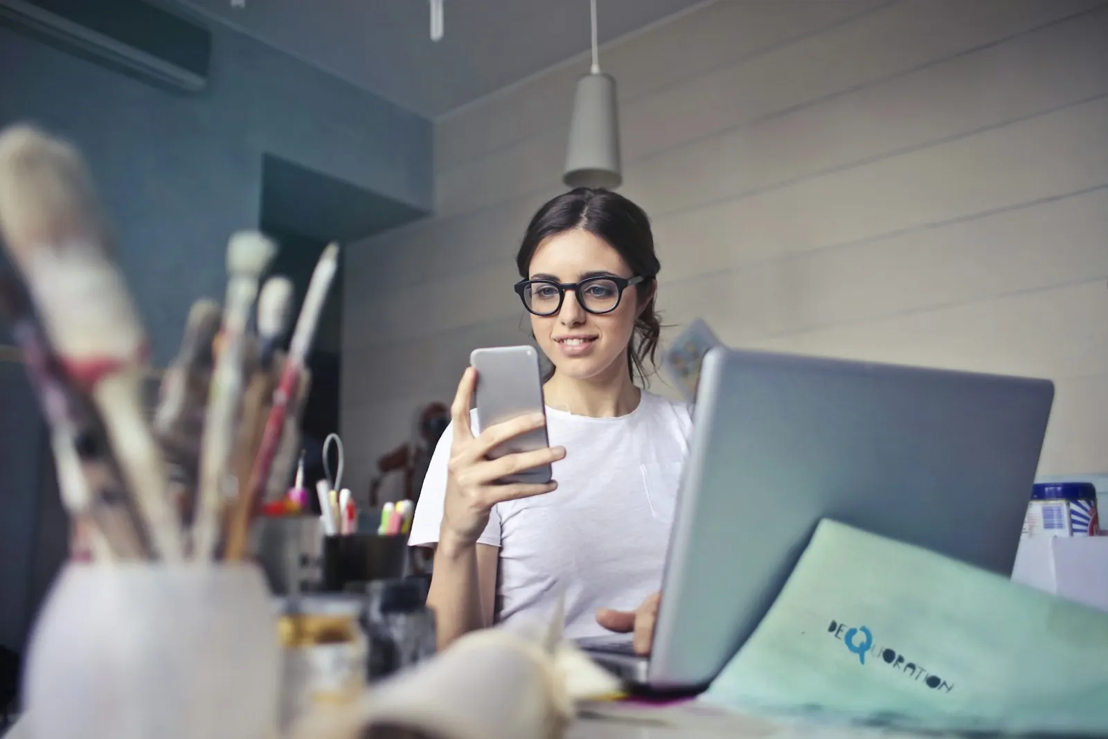A smiling professional replying to a customer chat on her phone at her desk