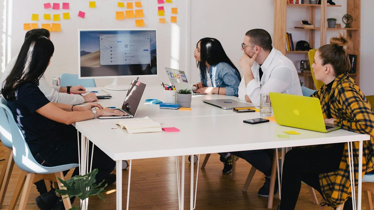 A marketing team working together around a table with laptops