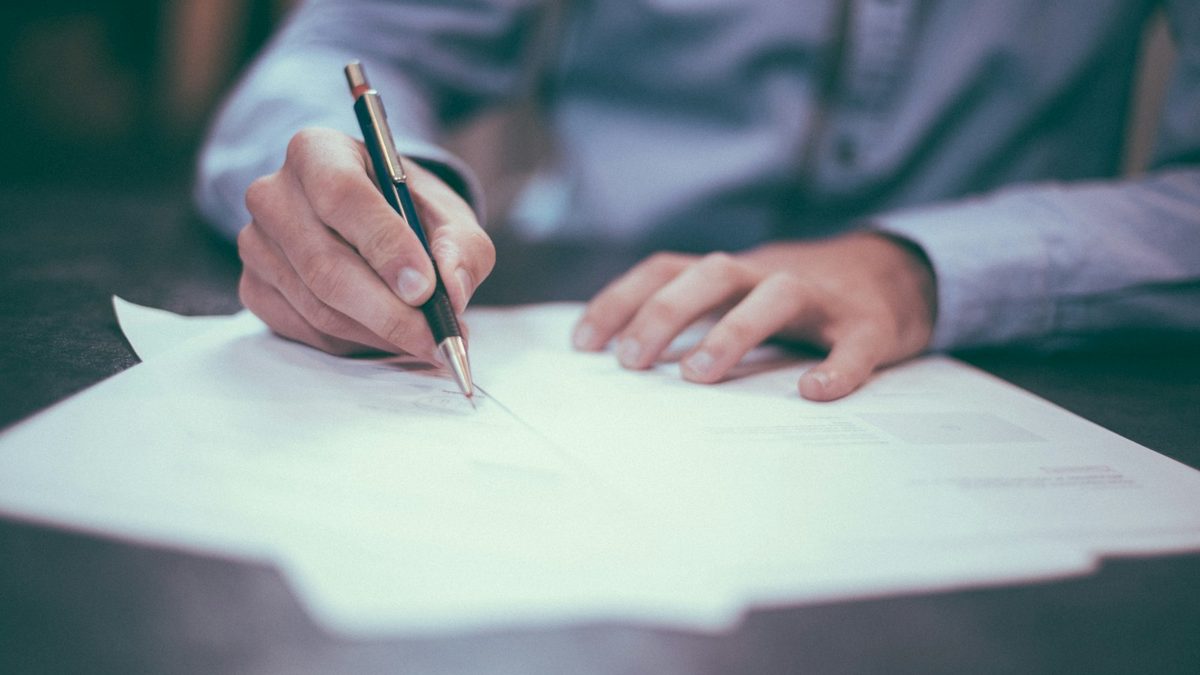 A finance professional signing a document at a desk