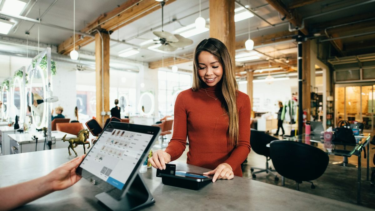 A store owner taking an order on a tablet at a bright shop counter