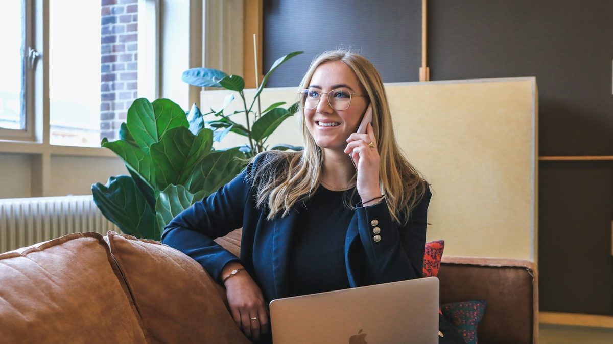 A businesswoman taking a phone call at her desk with a laptop