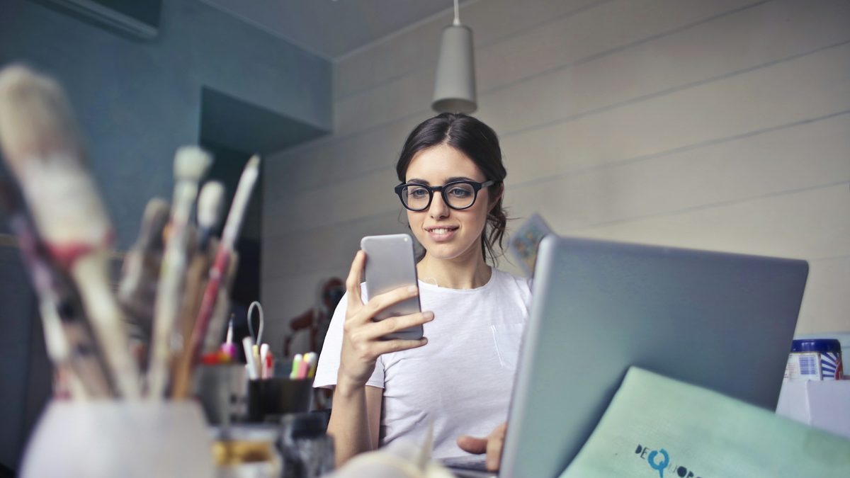 A smiling professional replying to a customer chat on her phone